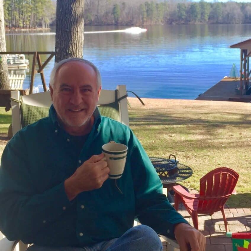 Bruce Swagler sitting by a lake holding a coffee mug